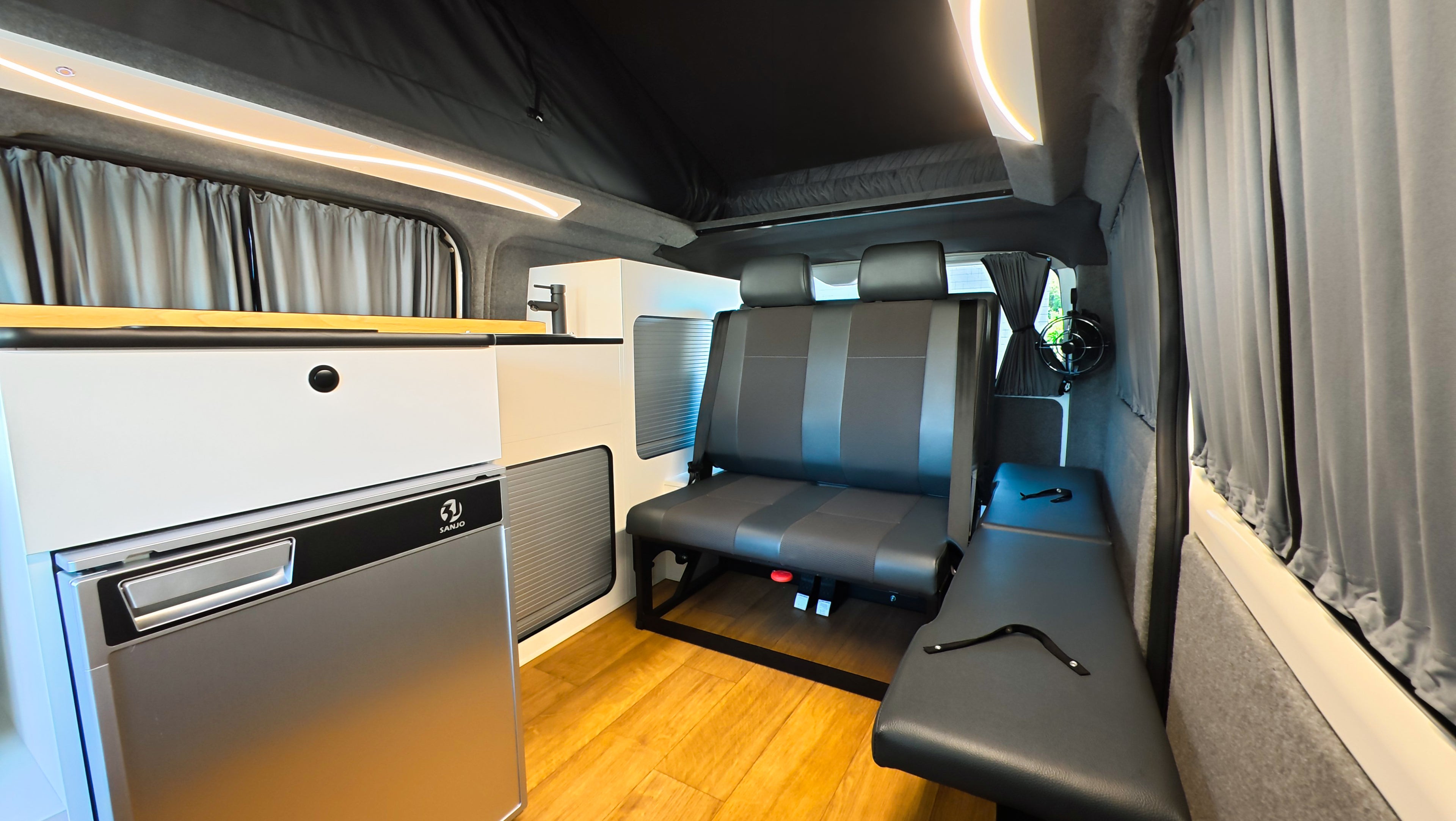 Interior of premium engineered Toyota Hiace Campervan. two seats which are suitable for children which can also be folded into a bed. Showing interior kitchen on Campervan